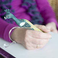 Schreibende Hand, Stift mit geschnitztem Vogel